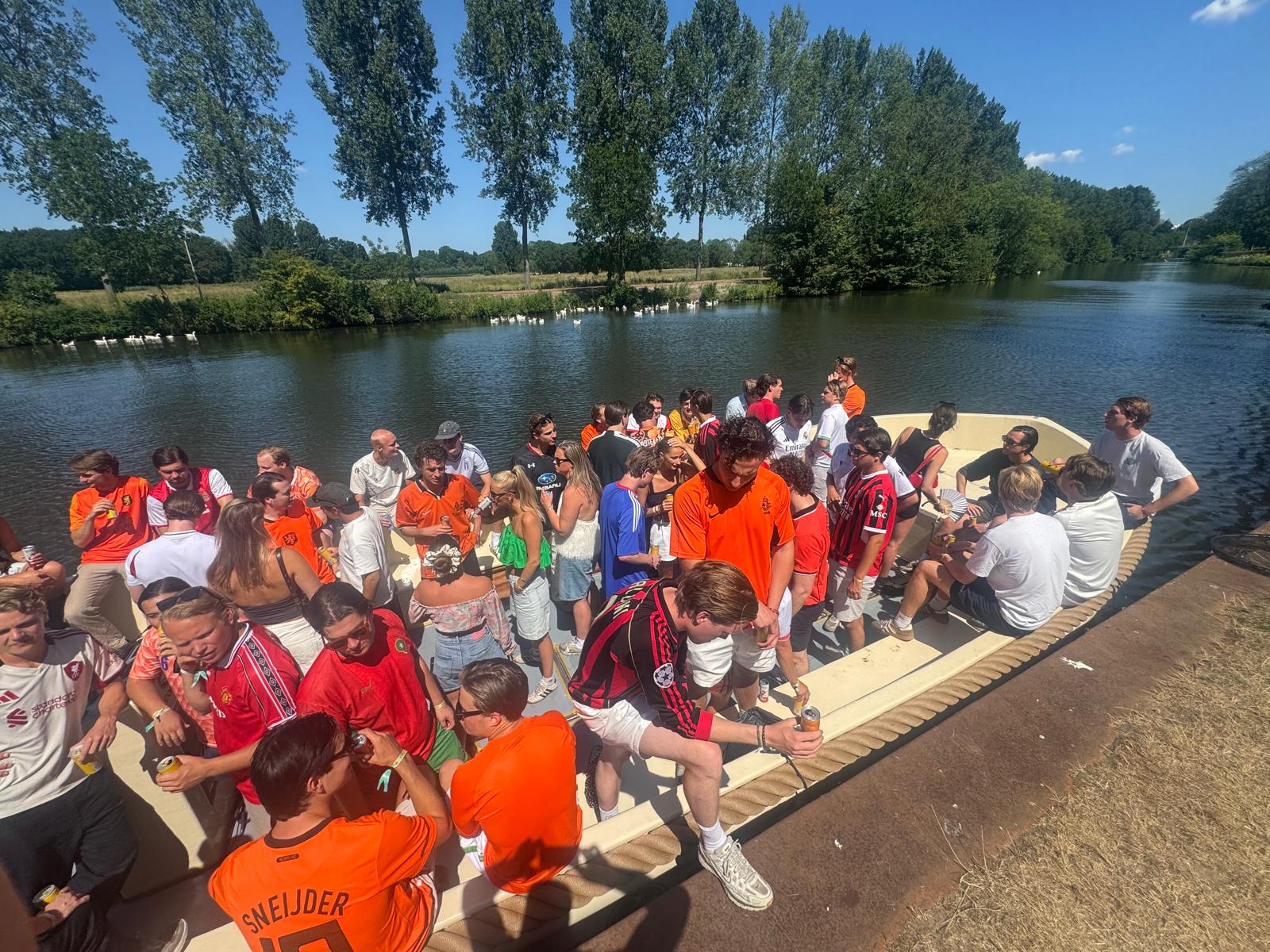 Large group of party-goers in orange on board a sloop during King's Day