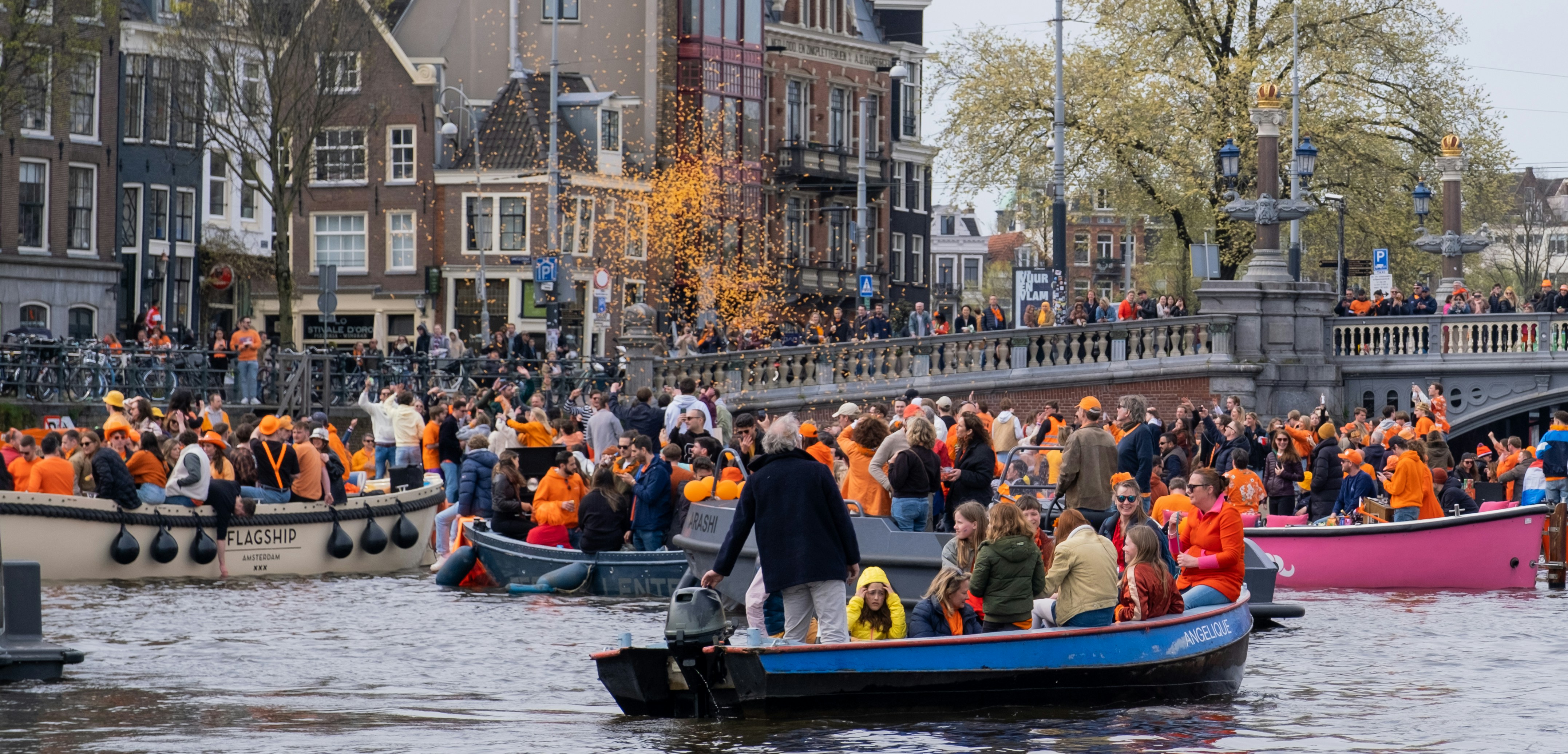 Boats full of people in orange on the canal during King's Day